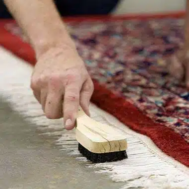 nettoyage tapis fait main avec brosse artisanale franges