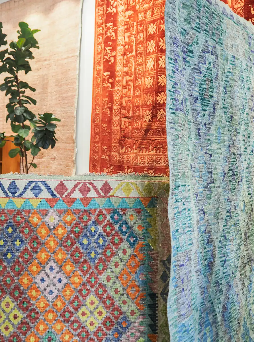Tapis kilim colorés aux motifs géométriques – inspiration déco Tapis kilim aux motifs géométriques colorés exposés avec textiles tissés bleus et plante verte