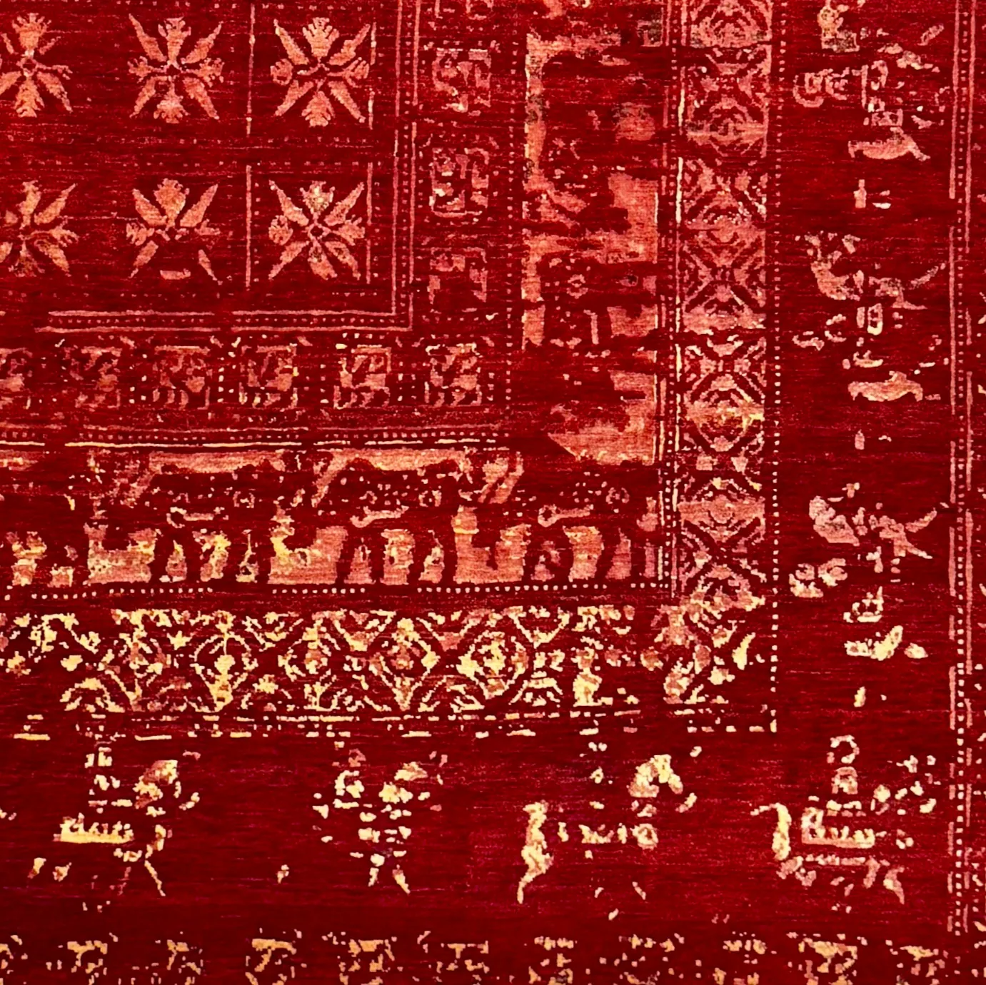 Détail tapis Pazyryk new design rouge, gros plan sur motifs géométriques floraux et frise animalière avec cavaliers en laine.