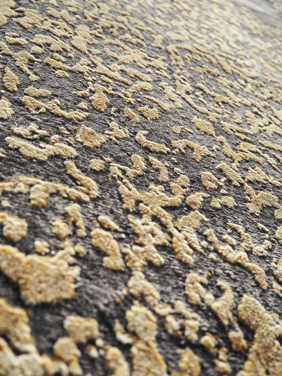 Texture velours tapis de luxe motifs floraux dorés en relief Macro du velours d'un tapis de luxe, motifs dorés en relief sur fond gris